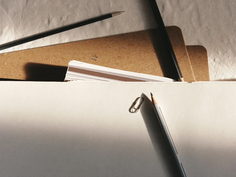 Ilustracja poglądowa: szczegół papierów, teczek i narzędzi pracy księgowej.